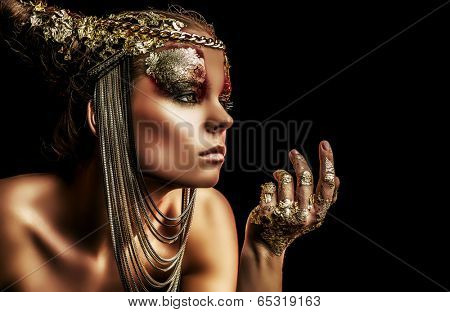 Art project: beautiful woman with golden make-up. Jewelry, make-up. Fashion. Over black background.