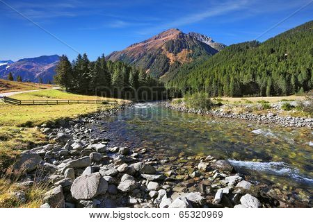  Idyllic landscape. Upper courses of falls - rather narrow fast seething small river among green mountain meadows.  National park Krimml in Austria