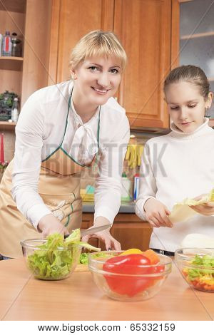 Caucasian Mother And Teenage Daughter Preparing Vegetables For  Salad In The Kitchen