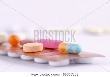 Colorful capsules and tablets on top a packed medication.