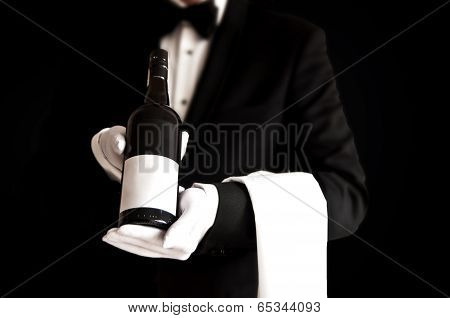Waiter In Tuxedo Holding A Bottle Of Red Wine