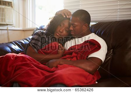 Couple Trying To Keep Warm Under Blanket At Home