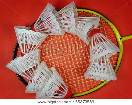 Red plastic shuttlecocks on badminton racket
