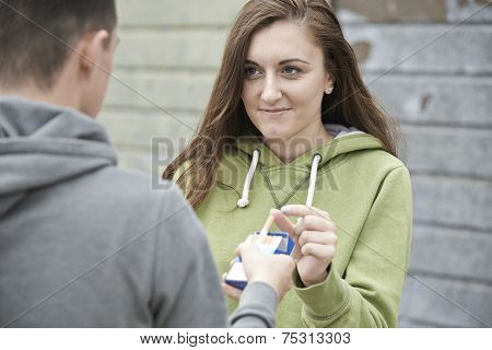 Boy Offering Teenage Girl Cigarette Outdoors