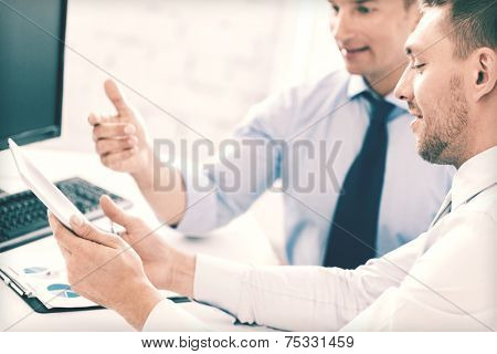 businesss and office concept - businessmen with notebook and tablet pc discussing graphs on meeting