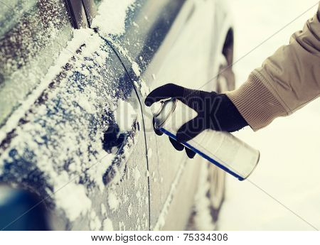 transportation, winter and vehicle concept - closeup of man hand with lock door de-icer