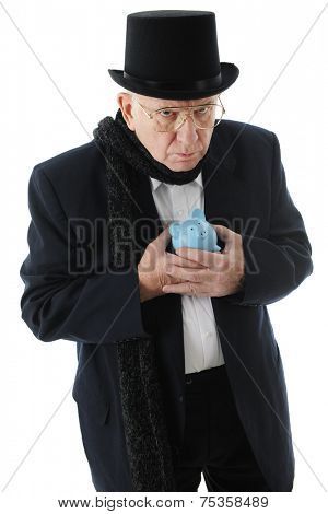 A grumpy old man in a top hat clinging miserly to his blue piggy bank.  On a white background. 