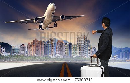 Man With Big Luggage Standing On Raod And Watching To Airplane Flying Over Urban Scene