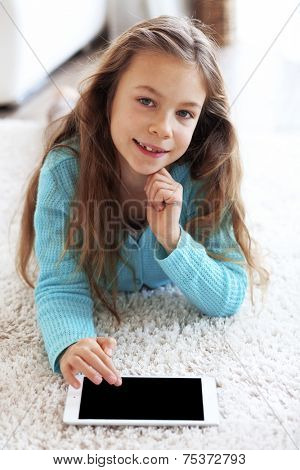 Child playing on ipad tablet pc sitting on a carpet at home