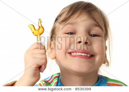 Niña sosteniendo Lollipop naranja, sonriendo y mirando a cámara, aislada en blanco