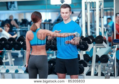 Beautiful girl in sports club with instructor