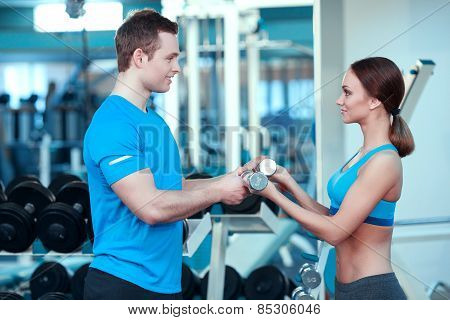 Beautiful girl in sports club with instructor