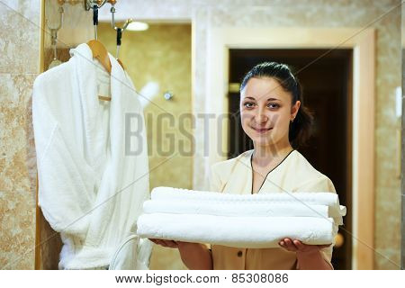 Hotel room service. female housekeeping worker with bedclothes linen in cart
