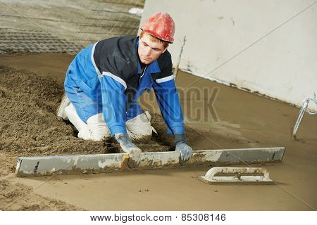 Plasterer at indoor concrete cement floor topping with float