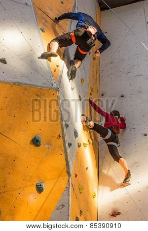two young people climbing on wall