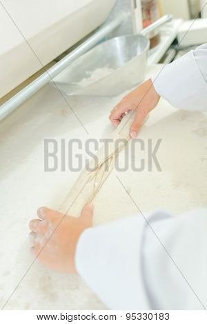 Hands rolling dough