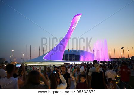 SOCHI, RUSSIA - JUL 27, 2014: Crowds of tourists walking near a bowl of the flame and singing Fountain in the park in the evening