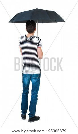 Back view man in jeans under an umbrella. Standing young guy. Rear view people collection. backside view person.  Isolated over white background. guy in the striped shirt standing under black umbrella