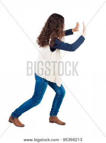 back view of woman pushes wall. Isolated over white background. Rear view people collection. backside view of person.  Girl in sleeveless fleece repels something right.