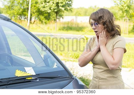 Suprised woman looking on parking ticket placed under windshield wiper