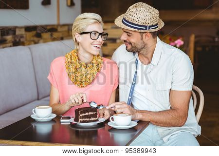 Cute couple on a date eating a piece of chocolate cake at the cafe