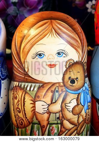 Matrioska representing a young girl with a toy bear. On sale in a christmas street market.