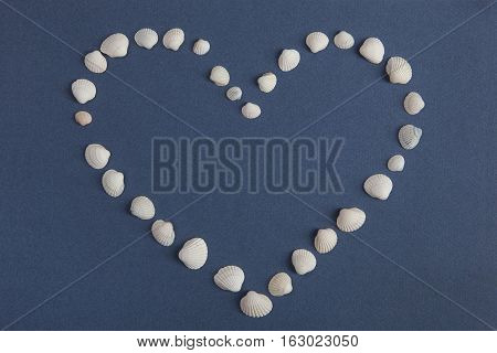 Heart from white seashells on a blue background. Valentine's Day, love, sea.Bright background.