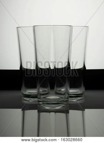 Three empty glasses on a blackand white background with reflection