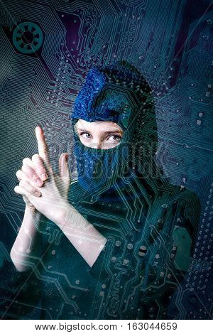 hacker girl in balaclava showing fingers gun on a background silhouette drawing circuit board. concept of computer hacking threats.