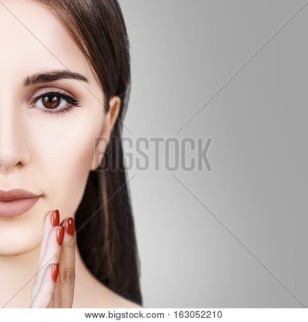Half-face portrait of beautiful sensitive woman over gray background