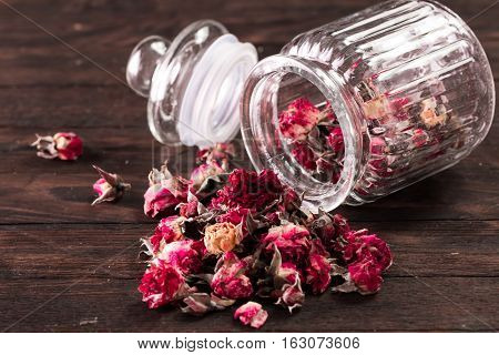 Rose Petals And Dried Flowers In Jar On Old Wooden Table. Healthy Concept