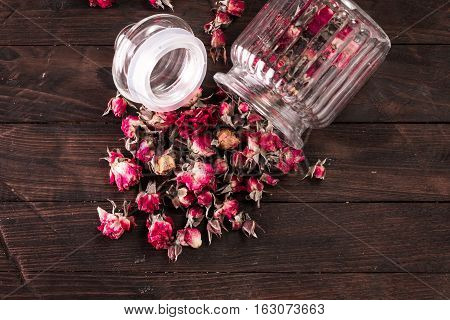 Rose Petals And Dried Flowers In Jar On Old Wooden Table. Healthy Concept