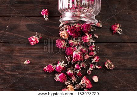 Rose Petals And Dried Flowers In Jar On Old Wooden Table. Healthy Concept