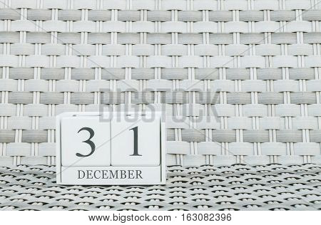 Closeup surface white wooden calendar with black 31 december word on blurred weave wood chair textured background with copy space selective focus at the calendar