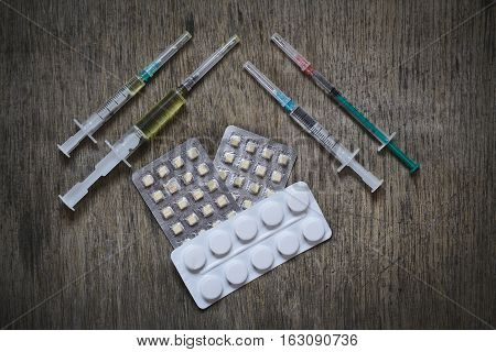 Drug syringe and cooked heroin with tablets in pack on a wooden tavle