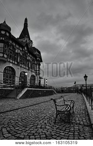 some lamps just beginning to shine on the czech lookout Vetruse on evening black and white photo with Usti nad Labem city on background