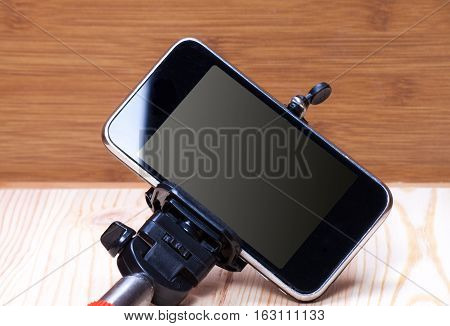 Monopod and phone on wood desk. Gadgetry on board.