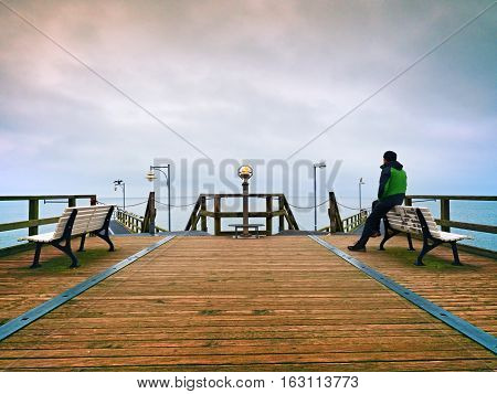 Man On Wooden Mole In Harbor Within Autumn Misty Day. Tourist At Handrail.