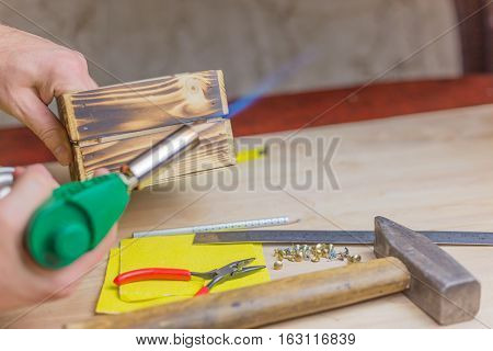 carpenter's tool firing wooden box with a blowtorch