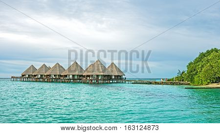 water bungalows against the blue ocean and tropical vegetation on the Maldivian island