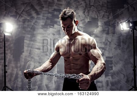 The Perfect male body. Awesome bodybuilder. One handsome sexual strong young man with muscular body holding rope with hand hanging on neck and shoulders standing posing in studio. strained biceps.