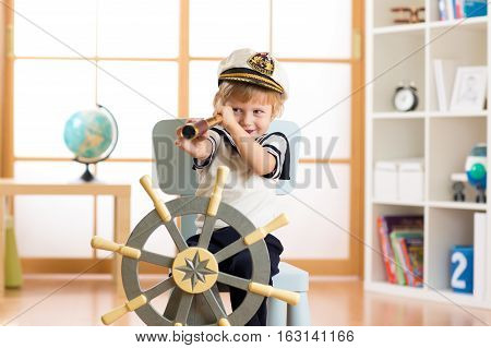 Child pretends to be a sailor. Little boy looking through spy glass playing at home.