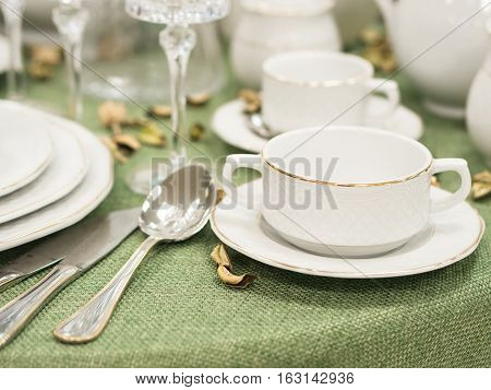 Set of new dishes on table with green tablecloth. Shallow DOF