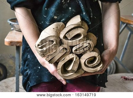 Master potter girl holding a many cut and twisted layers roll of clay pieces. Creative studio potter. Workplace wizard Crock pottery