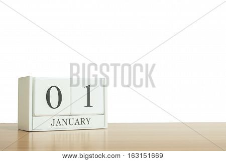 Closeup surface white wooden calendar with black 1 january word on blurred brown wood desk isolated on white background with copy space selective focus at the calendar