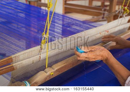 Hands of an old woman who was arrested instruments inserted thread. The loom by hand which is a craft of weaving silk in Thailand.