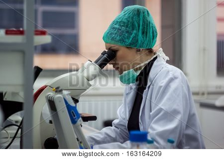 Beautiful Female Medical Or Scientific Researcher Or Woman Doctor Looking Through A Microscope In A