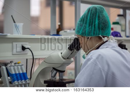 Beautiful Female Medical Or Scientific Researcher Or Woman Doctor Looking Through A Microscope In A