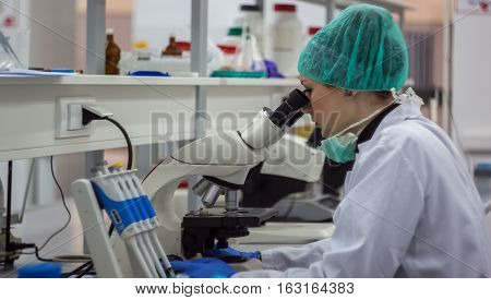 Beautiful Female Medical Or Scientific Researcher Or Woman Doctor Looking Through A Microscope In A