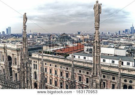 Old photo with view over Milan from the top of the gothic cathedral Milan Cathedral Italy. Church's roof statues in the foreground skyscrapers of the city in the background.Vintage processing.